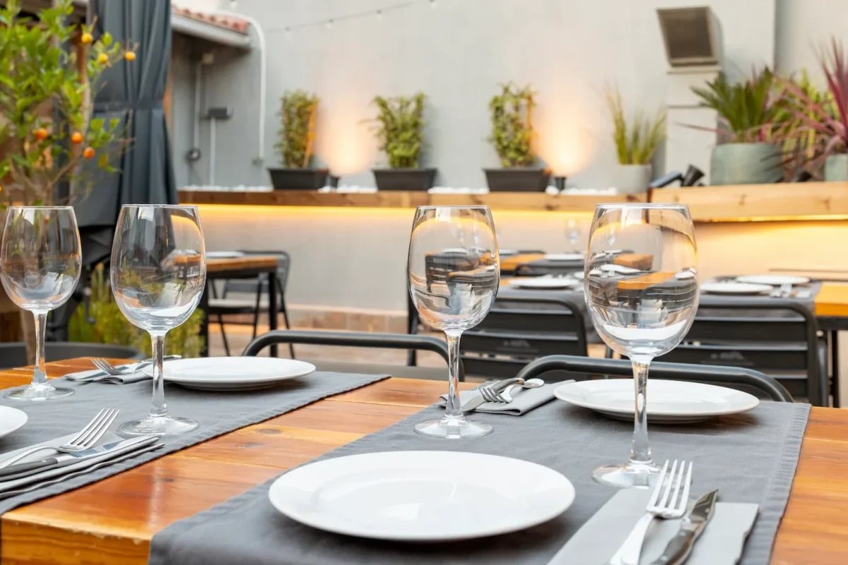 Terraza del restaurante Es Pati en Palma de Mallorca con mesas de madera vestidas y copas de vino al atardecer