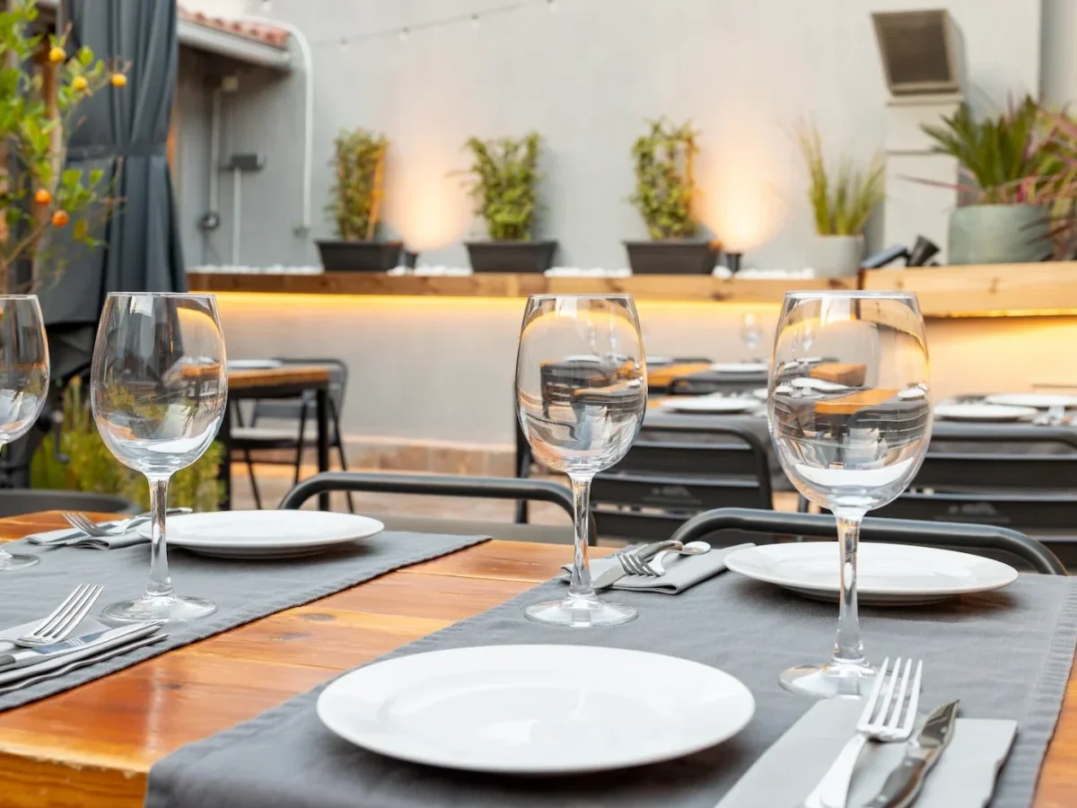 Terraza del restaurante Es Pati en Palma de Mallorca con mesas de madera vestidas y copas de vino al atardecer